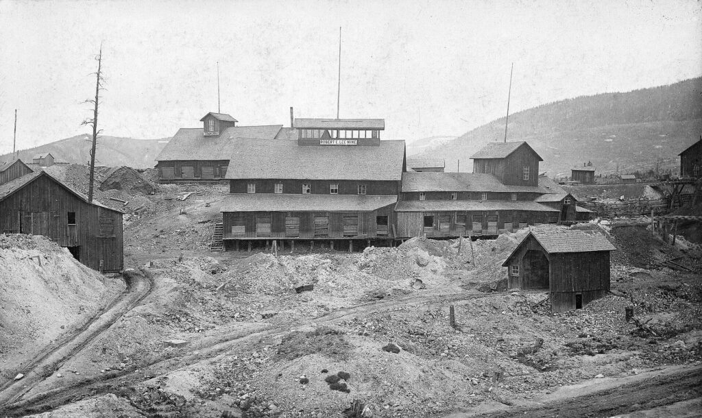 Black and white photograph of the Robert E. Lee Mine buildings and tailings in Leadville, with rail tracks in the foreground